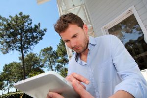 Portrait of smiling man working at home on tablet