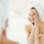 Happy girl looking at her face in mirror after bath